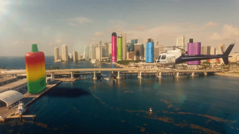 A giant inflatable vape pen with a rainbow gradient design and green cap, standing prominently near the waterfront.